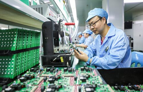 Employees work on a production line of electric car charging station at a factory in Ruichang