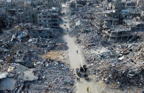 People make their way past the rubble of houses in Rafah