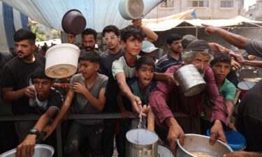 Palestinian children queue for a portion of hot food distributed by a charity kitchen at the Nuseirat refugee camp in the central Gaza Strip on July 15.