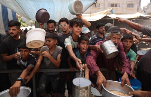 Palestinian children queue for a portion of hot food distributed by a charity kitchen at the Nuseirat refugee camp in the central Gaza Strip on July 15.