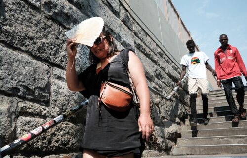 A woman shades herself from the sun as she tries to keep cool along the Brooklyn Bridge during a heat wave.