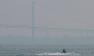 A wave runner navigates the Detroit River as a haze of Canadian wildfire smoke blankets the Ambassador Bridge and creates poor air quality in Detroit