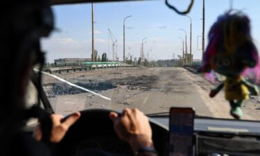 A car with volunteers drives over a damaged bridge after Russian air bomb attacks in Kherson