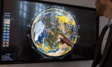A worker points to a monitor displaying current satellites in orbit and real-time communications across the globe at the Iridium Communications Inc. Satellite Network Operations Center in Leesburg