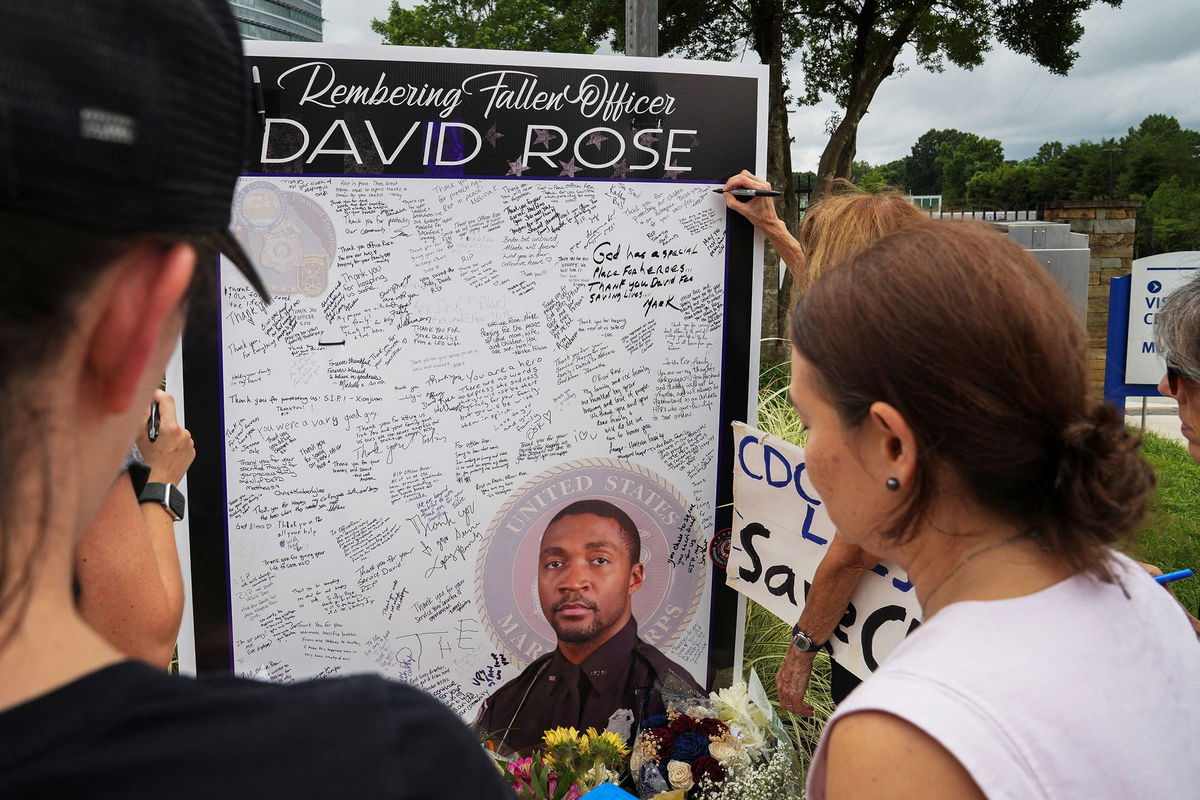 <i>Megan Varner/Reuters via CNN Newsource</i><br/>Community members pay their respects to David Rose