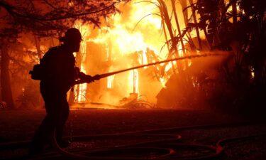 Los Angeles County firefighters spray water on a burning home as the Eaton Fire moved through the area on January 8 in Altadena