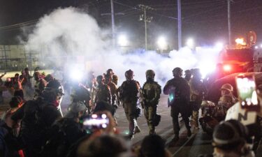 Federal law enforcement agents stand off against demonstrators protesting outside of an immigrant processing center on September 27