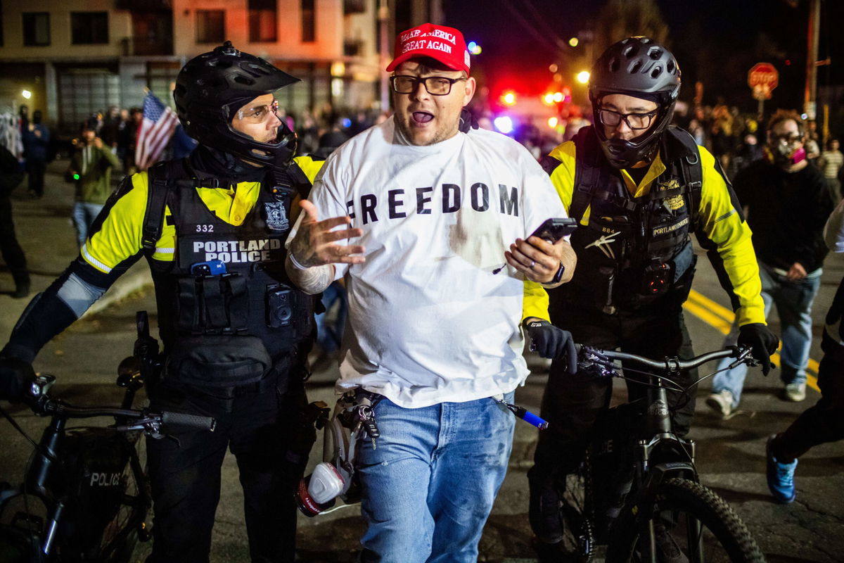 <i>Ethan Swope/AP via CNN Newsource</i><br/>Portland police officers talk to a man near a US Immigration and Customs Enforcement facility in Portland Sunday.